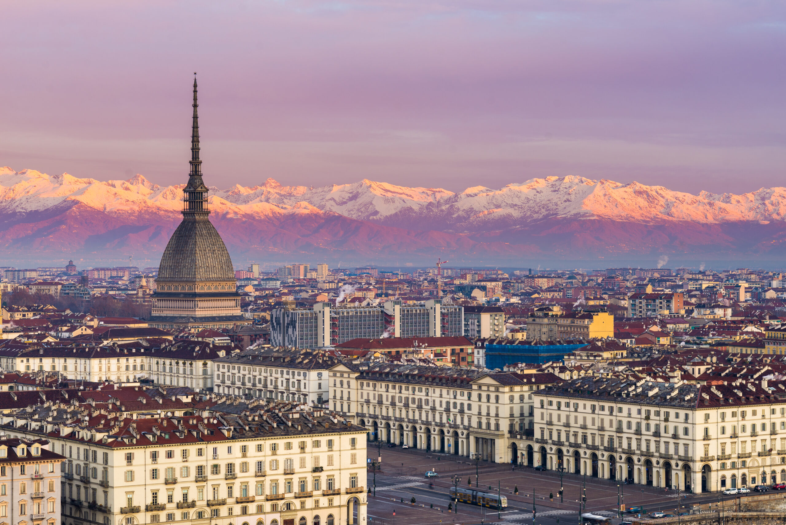 Torino (Turin, Italy): cityscape at sunrise with details of the Mole Antonelliana towering over the city. Scenic colorful light on the snowcapped Alps in the background.